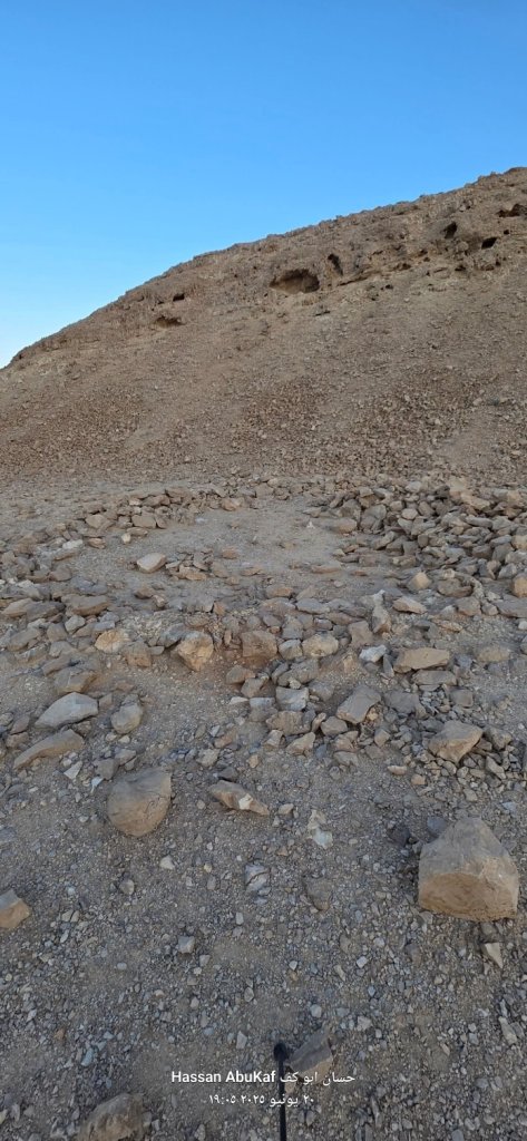 صورة لجزء من مسار نقب أبو طاقية، تُظهر تضاريس جبلية قاحلة مع صخور متناثرة والسماء الزرقاء في الخلفية.