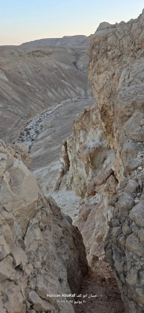 منظر طبيعي من نقب أبو طاقية، يظهر الوادي بين الصخور الجيرية، مع تضاريس صحراوية مميزة وألوان دافئة في الأفق.