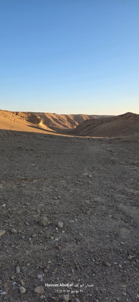 منظر طبيعي لصحراء نقب أبو طاقية يظهر واديًا عميقًا محاطًا بالتضاريس الجبلية تحت سماء زرقاء صافية.